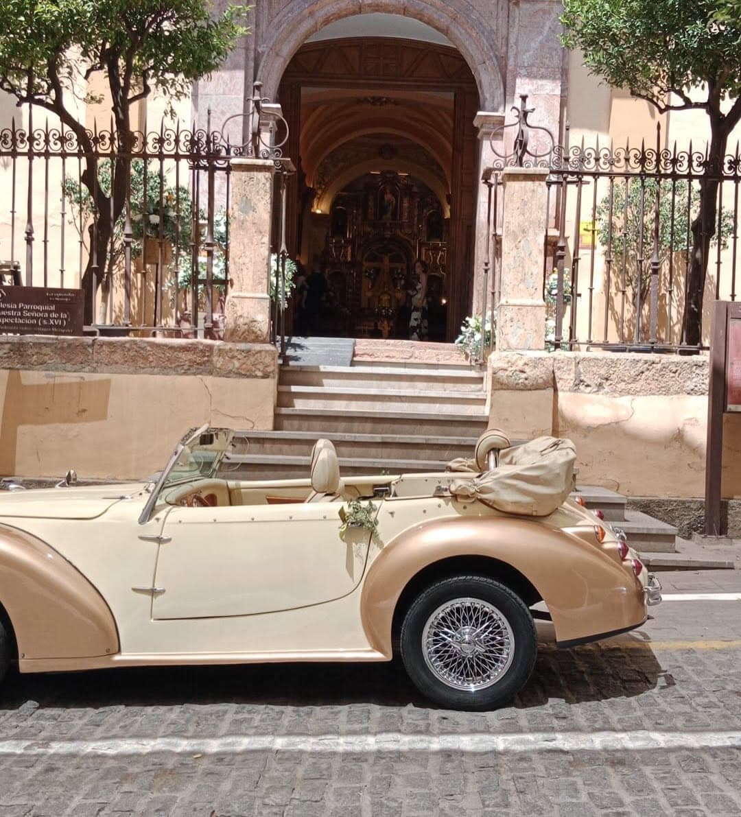 Novios en un coche clásico a la puerta de una iglesia