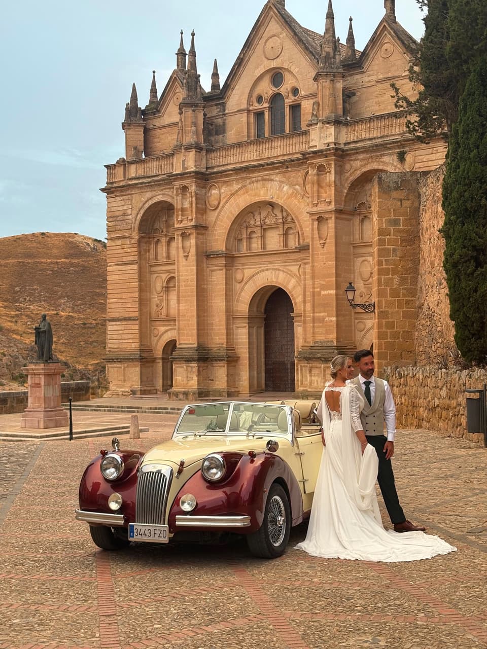 Novios junto a un coche clásico ante la Colegiata de Santa María de Antequera