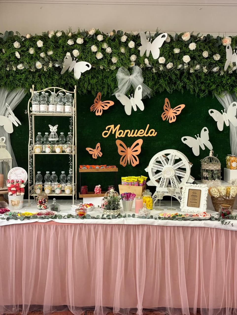 Mesa dulce en rosa con mariposas y pared de flores