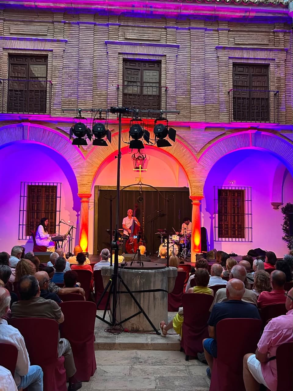 Concierto de noche en un patio de arcos iluminado